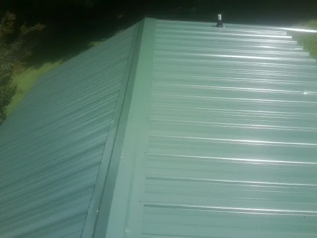 New green metal panels meeting at the ridge of a roof — Flat Roof Repair work by our crew in Grafton