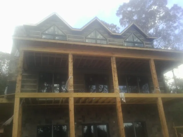 Dormers and porch framing on a large log home under construction — Roof Coating work by our crew in Grafton