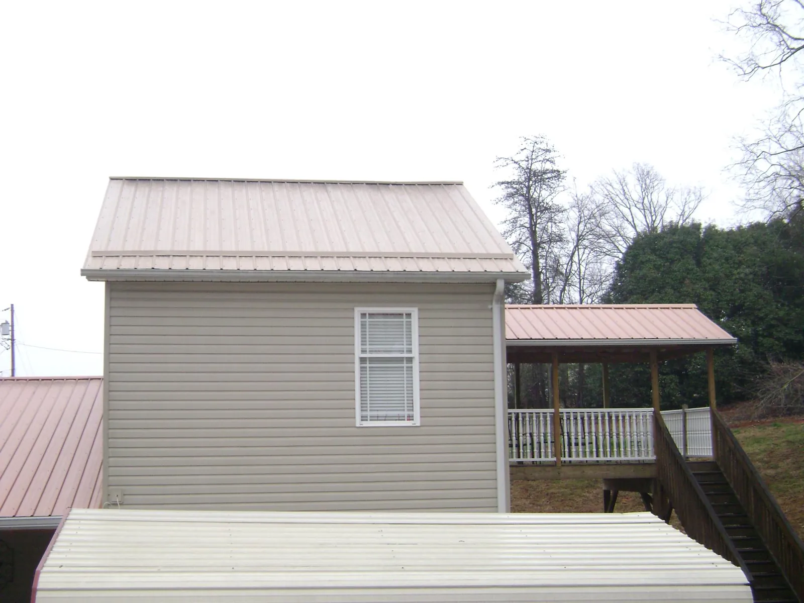 Tan metal roofs on a two story addition and attached porch, from a Roof Replacement job in Grafton